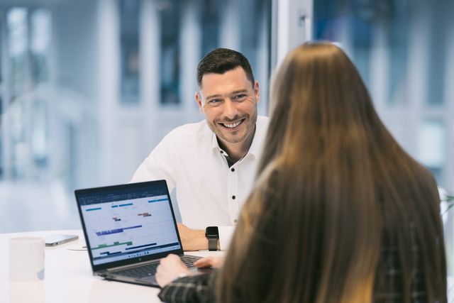 Mitarbeiter im Gespräch am Laptop, Arbeitsszene im Büro
