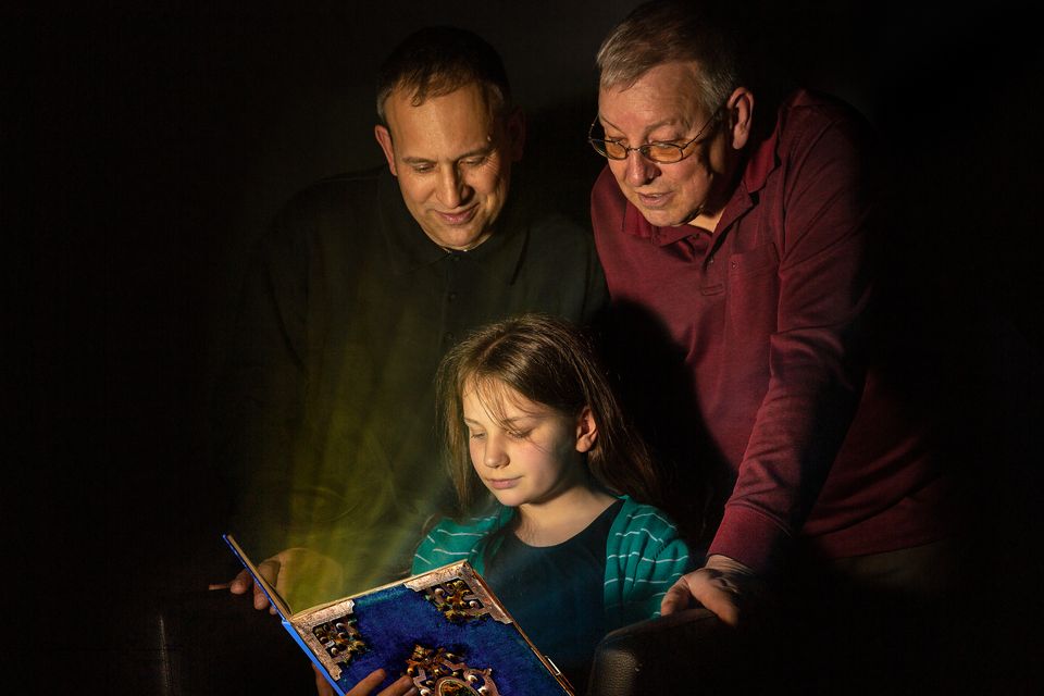 Vater und Großvater lesen mit Kind