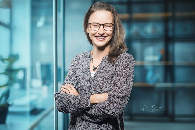 Businessportrait einer Frau mit verschränkten Armen vor Glaswand