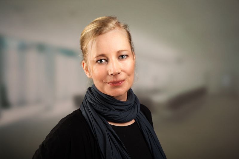 Blonde Frau mit Schal vor dunklem Hintergrund