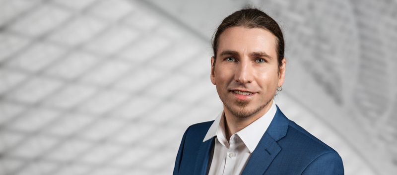 Mann im blauen Sakko vor heller Architektur