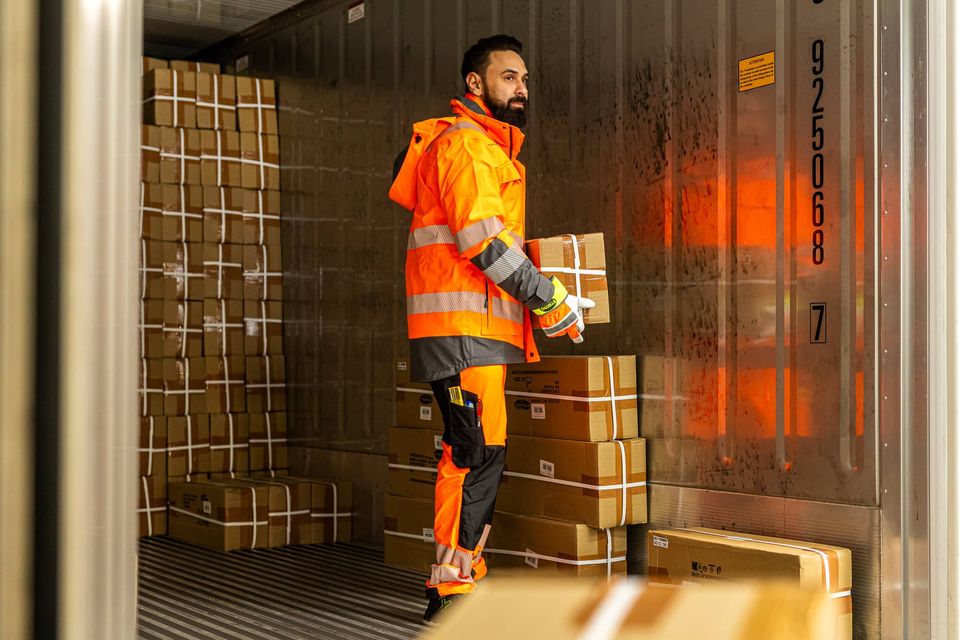 Lagerarbeiter in Warnkleidung zwischen Kartons