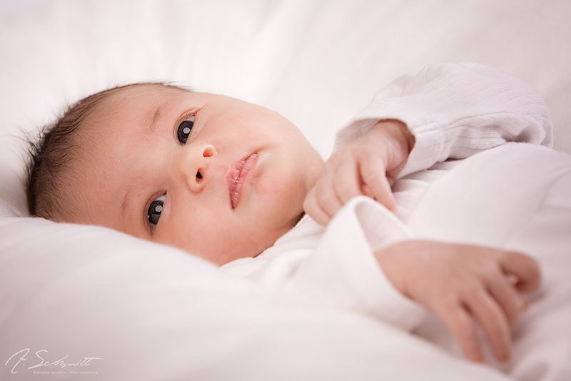 Baby liegt auf weißer Decke