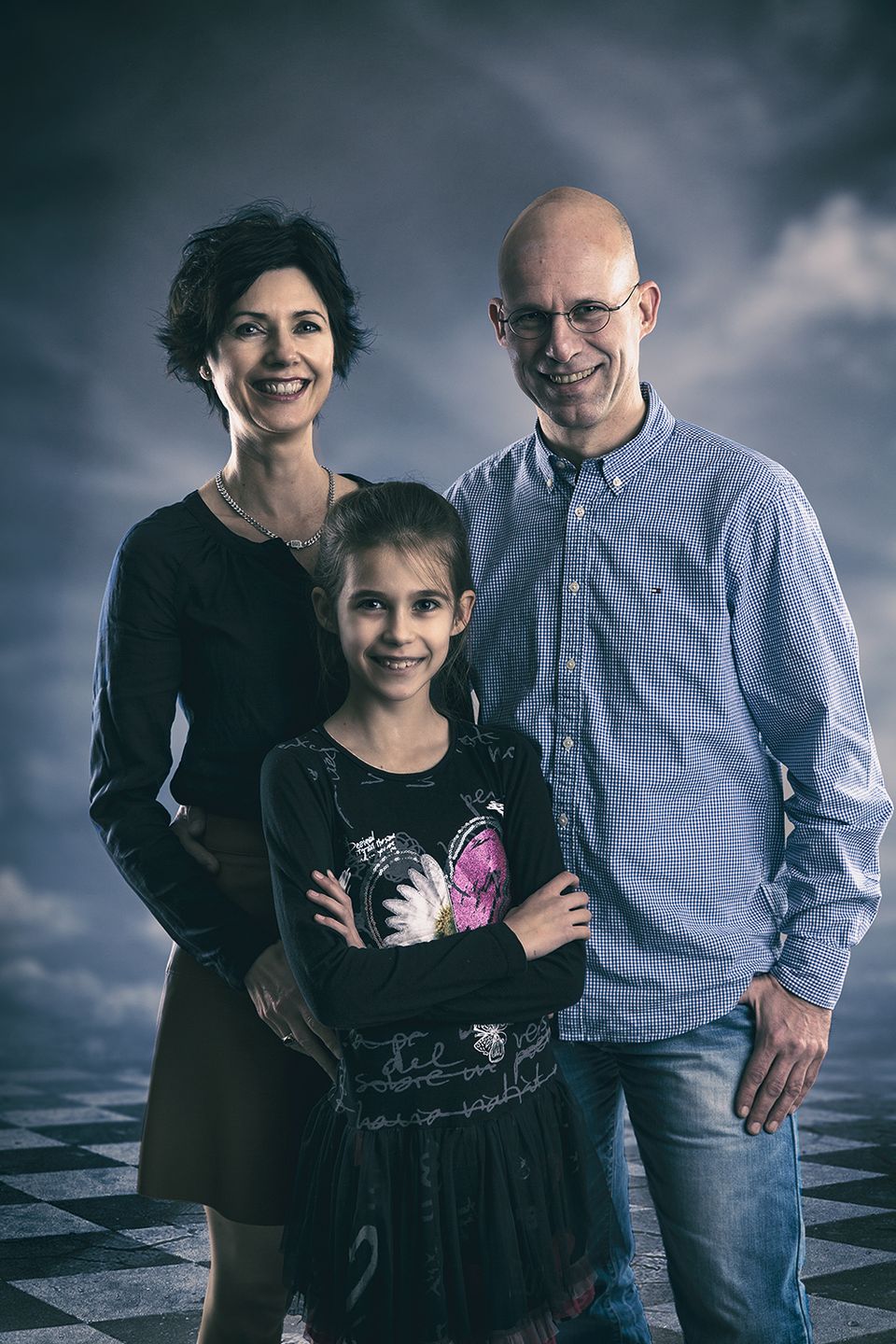 Eltern mit Tochter vor dunklem Himmel