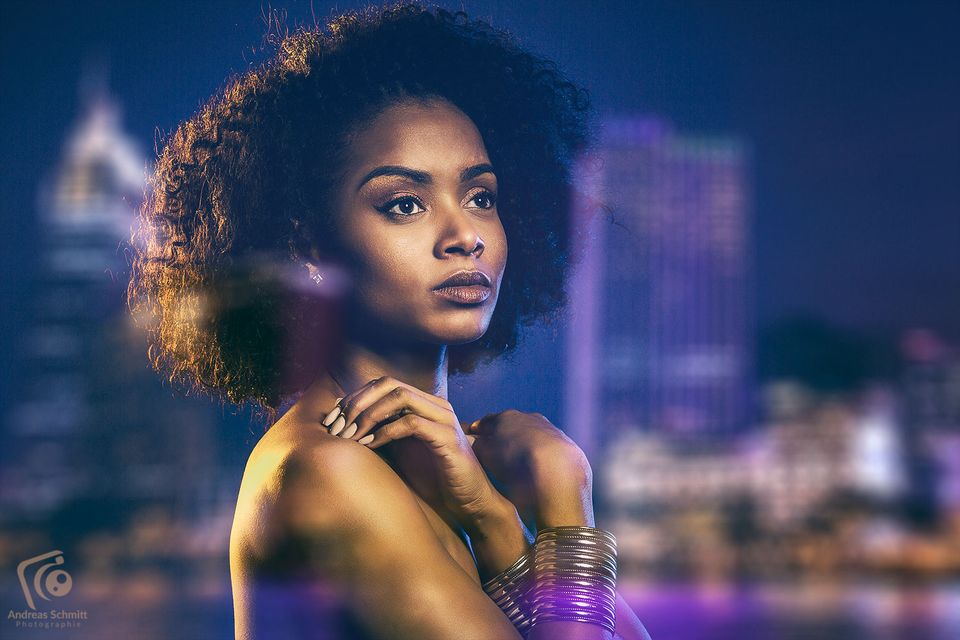 Frau mit Afro vor der Skyline bei Nacht