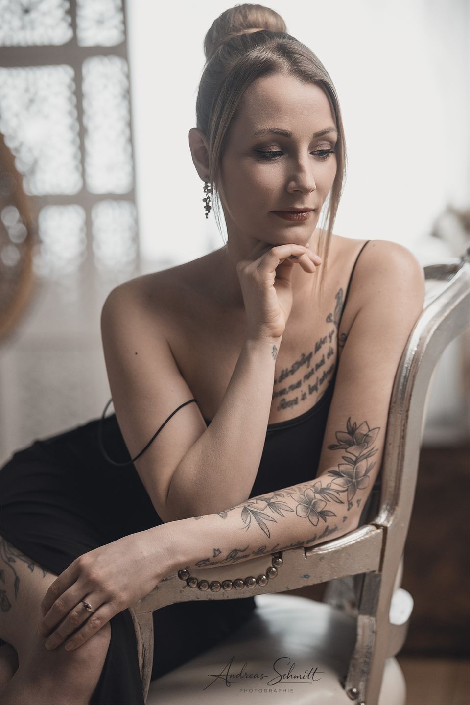 Frau mit Tattoos sitzt am Fenster