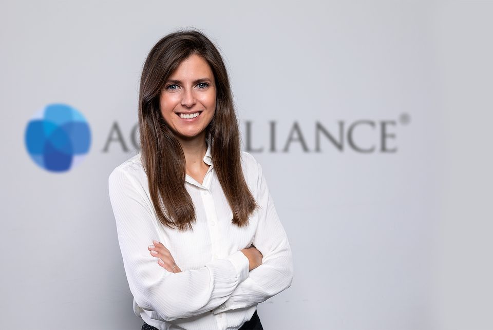 Frau in weißer Bluse vor dem Aquilliance-Logo