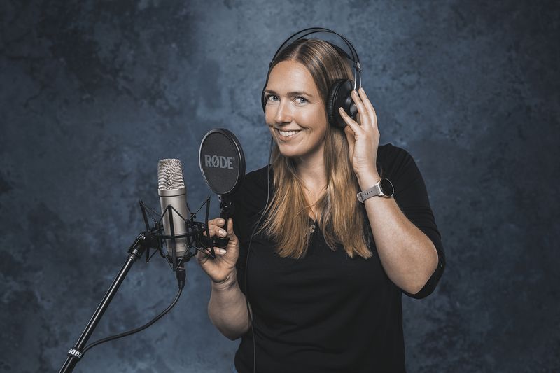 Frau mit Kopfhörer am Mikrofon, Podcast-Aufnahme